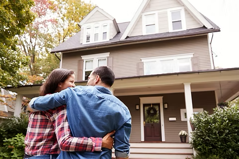 a couple hugging in front of their new home
